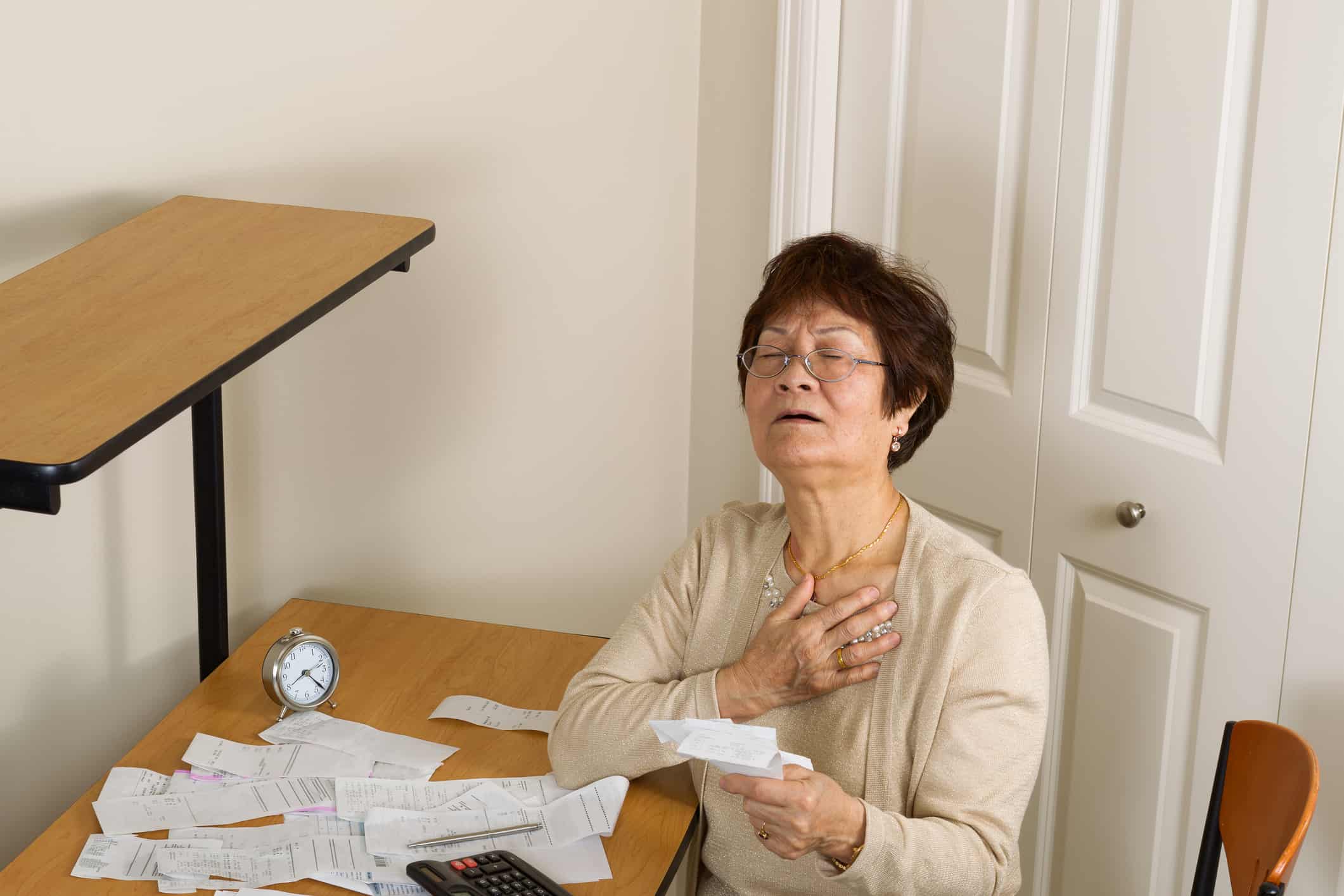 Senior woman feeling ill with her financial bills.