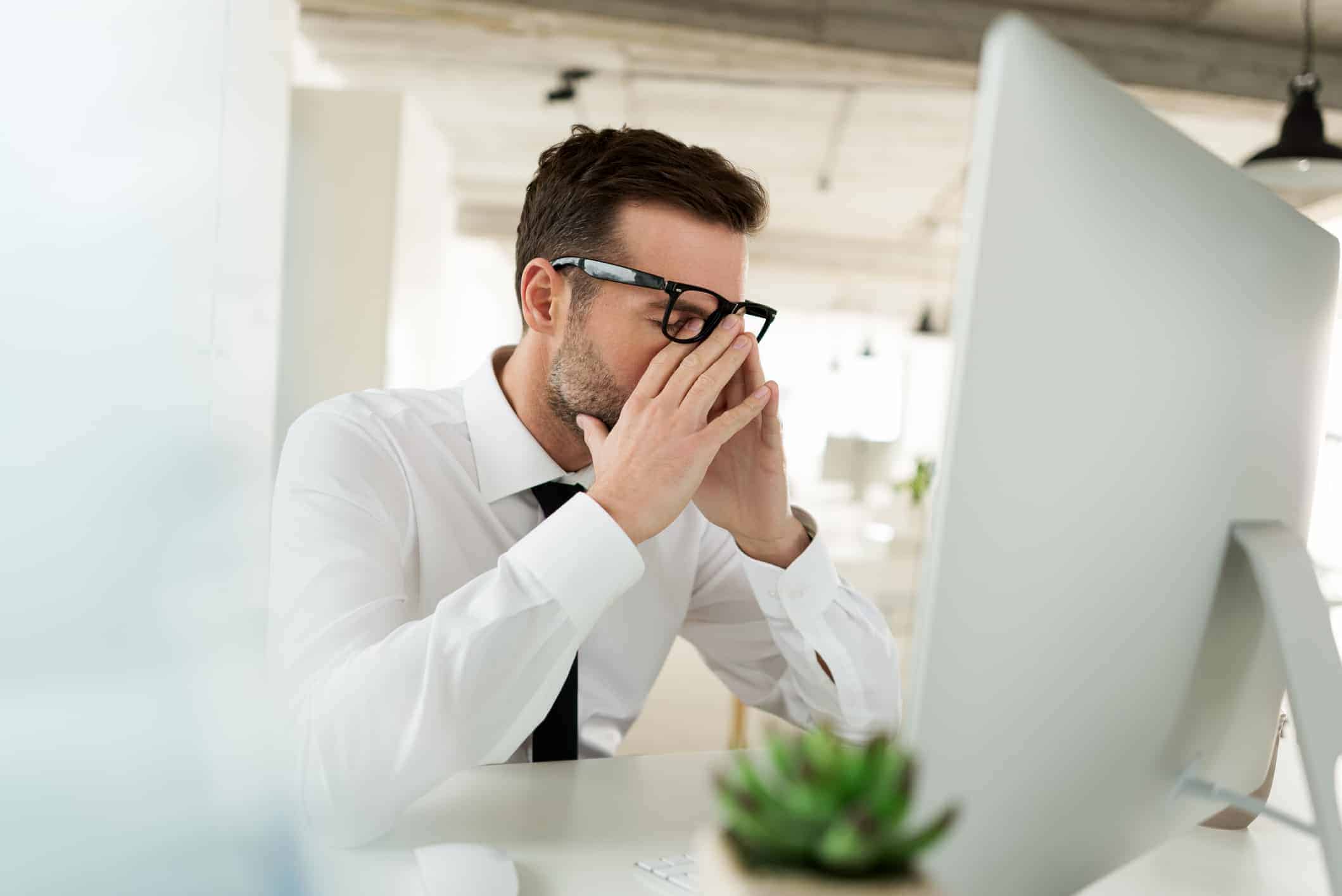 Worried businessman sitting at the desk in his office and using computer.